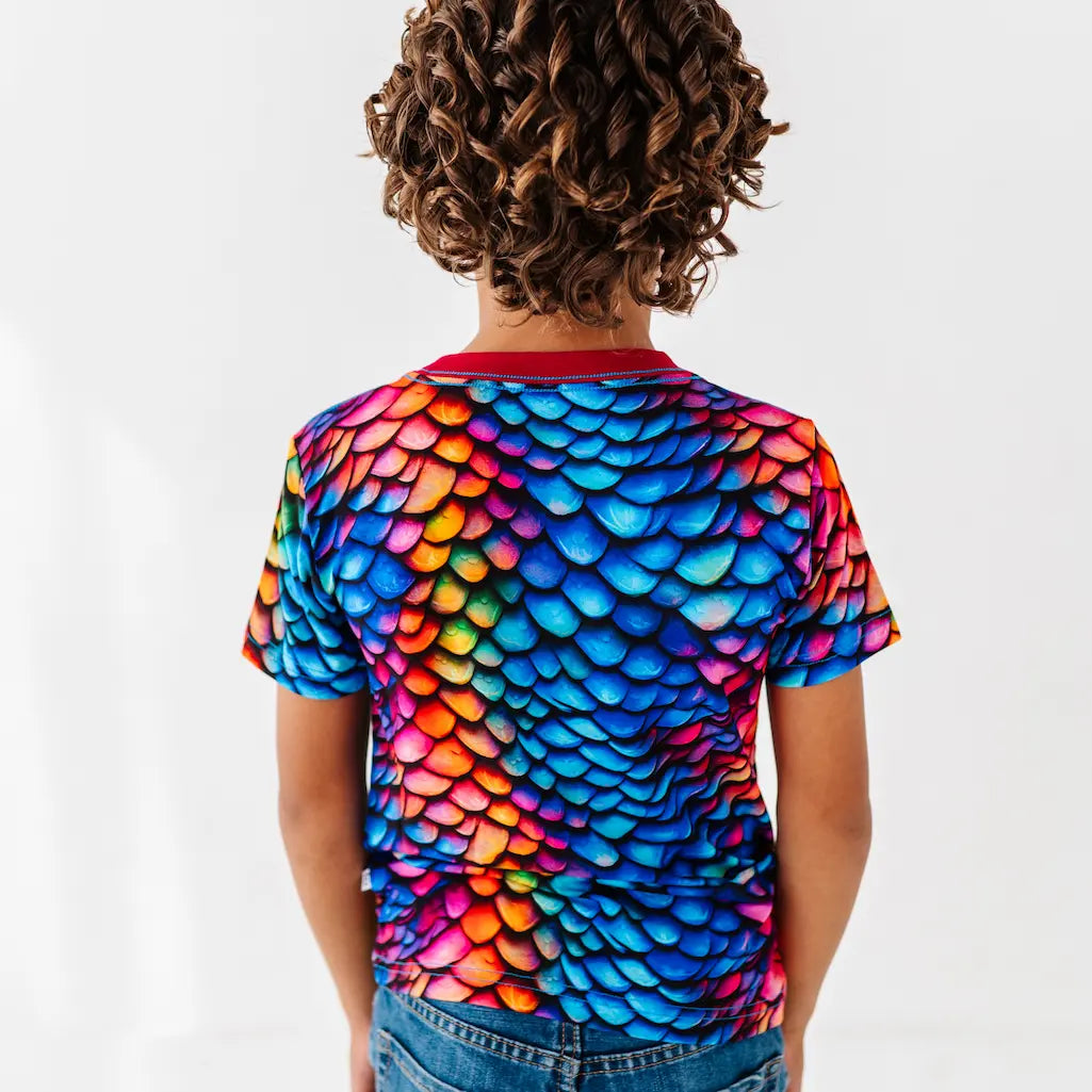 Child wearing a colorful fish scale pattern shirt on a white background