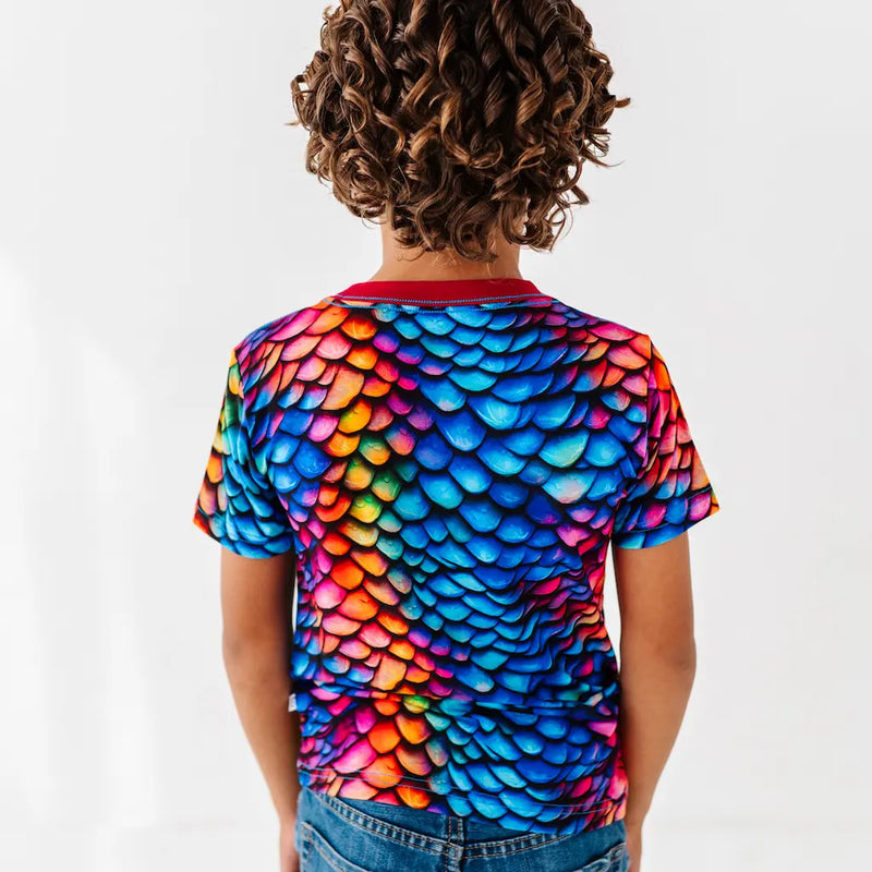 Child wearing a colorful fish scale pattern shirt on a white background