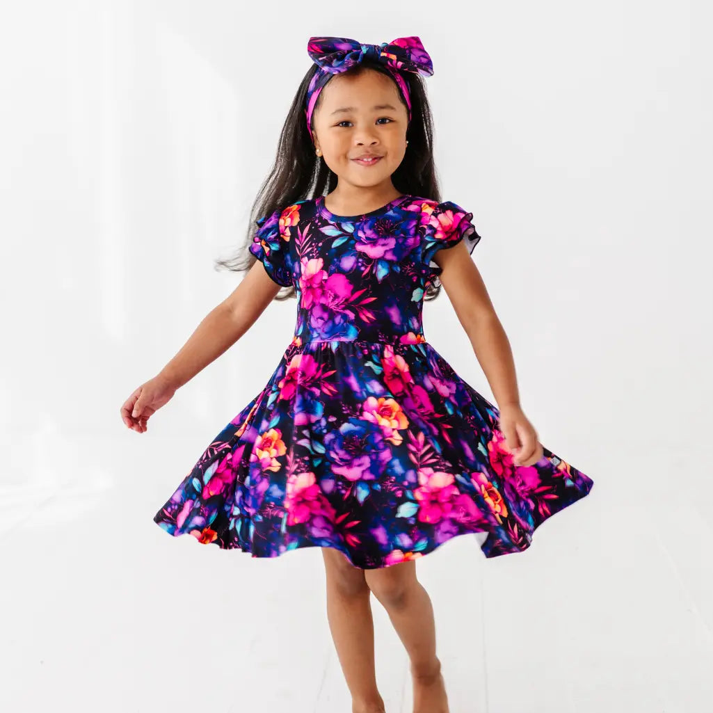 Young girl wearing a colorful floral dress and headband on a white background