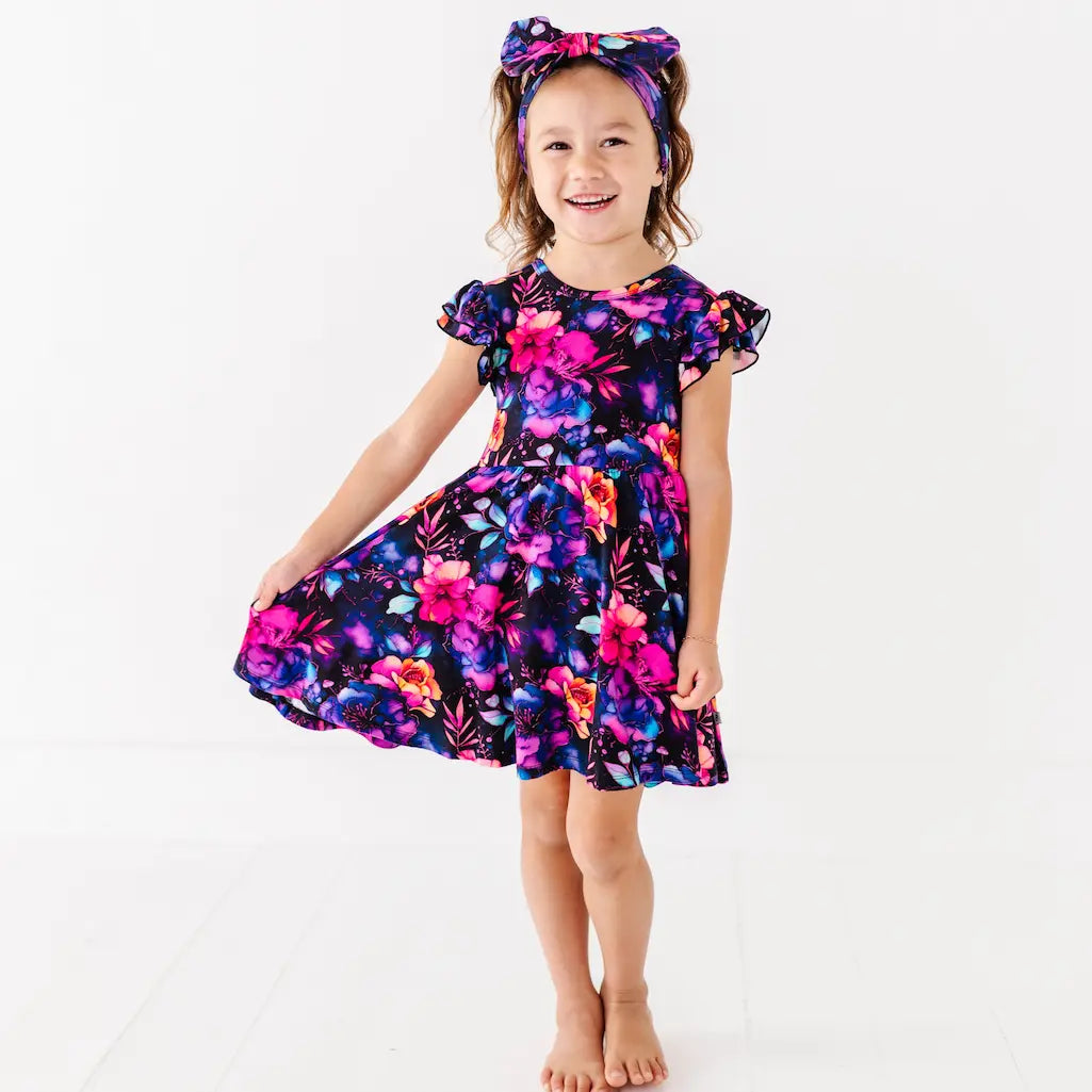 Young girl wearing a colorful floral dress on a white background