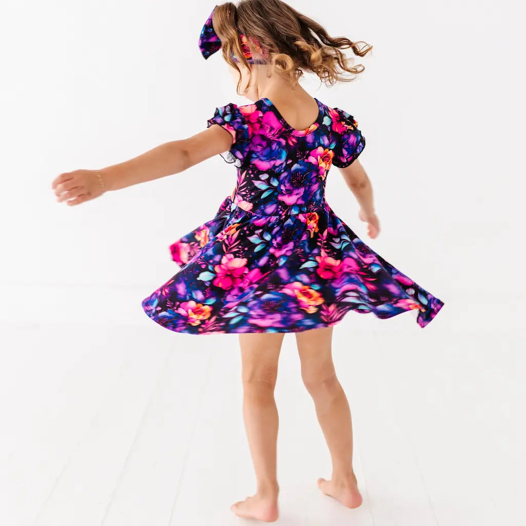 Child wearing a colorful dress with a butterfly pattern on a white background