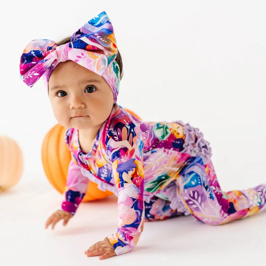Baby in colorful outfit with headband on a white background