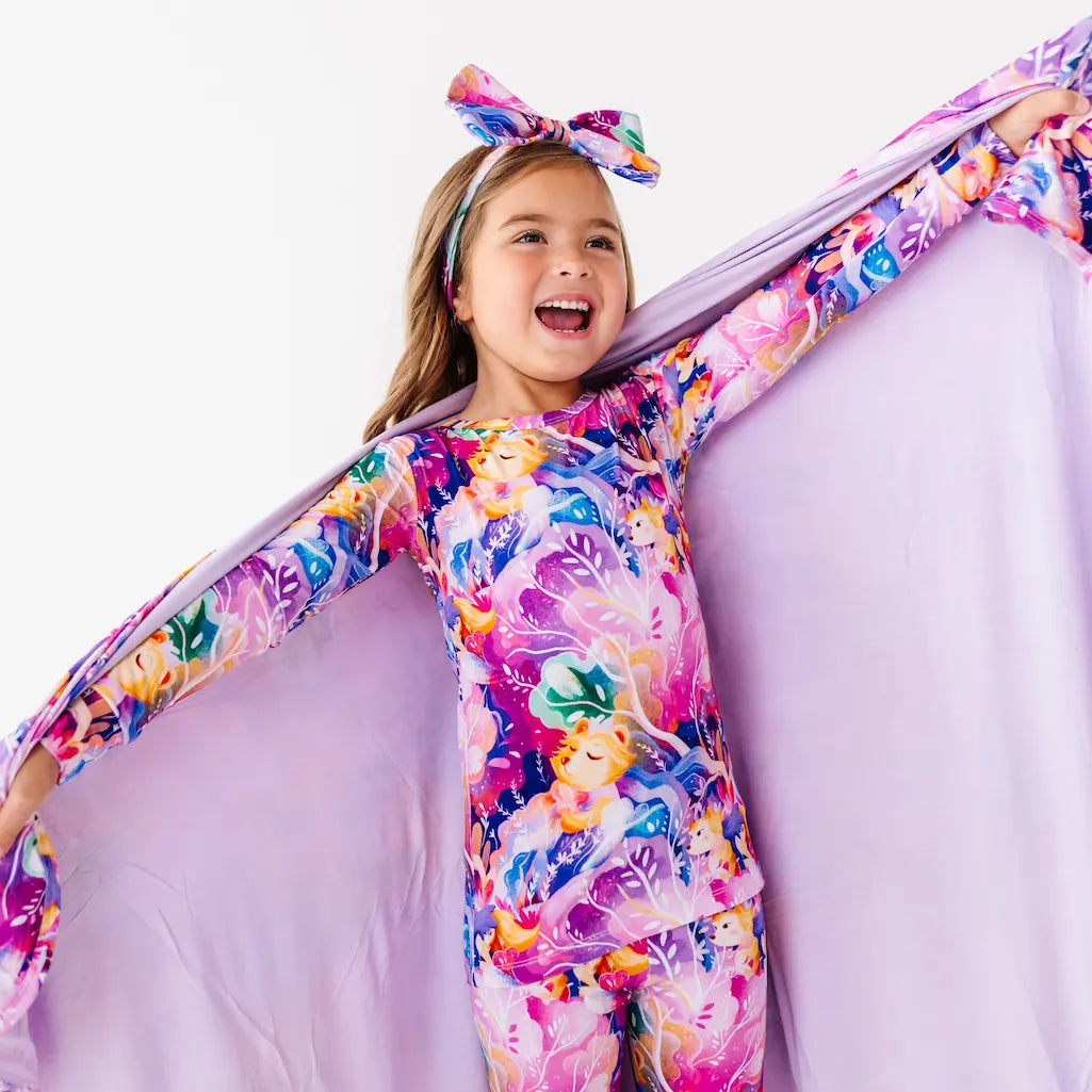 Child wearing a colorful floral dress with a matching headband on a white background