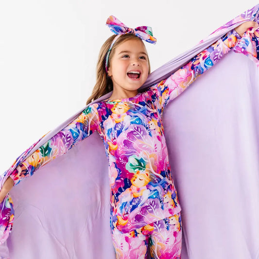 Child wearing a colorful floral dress with a matching headband on a white background