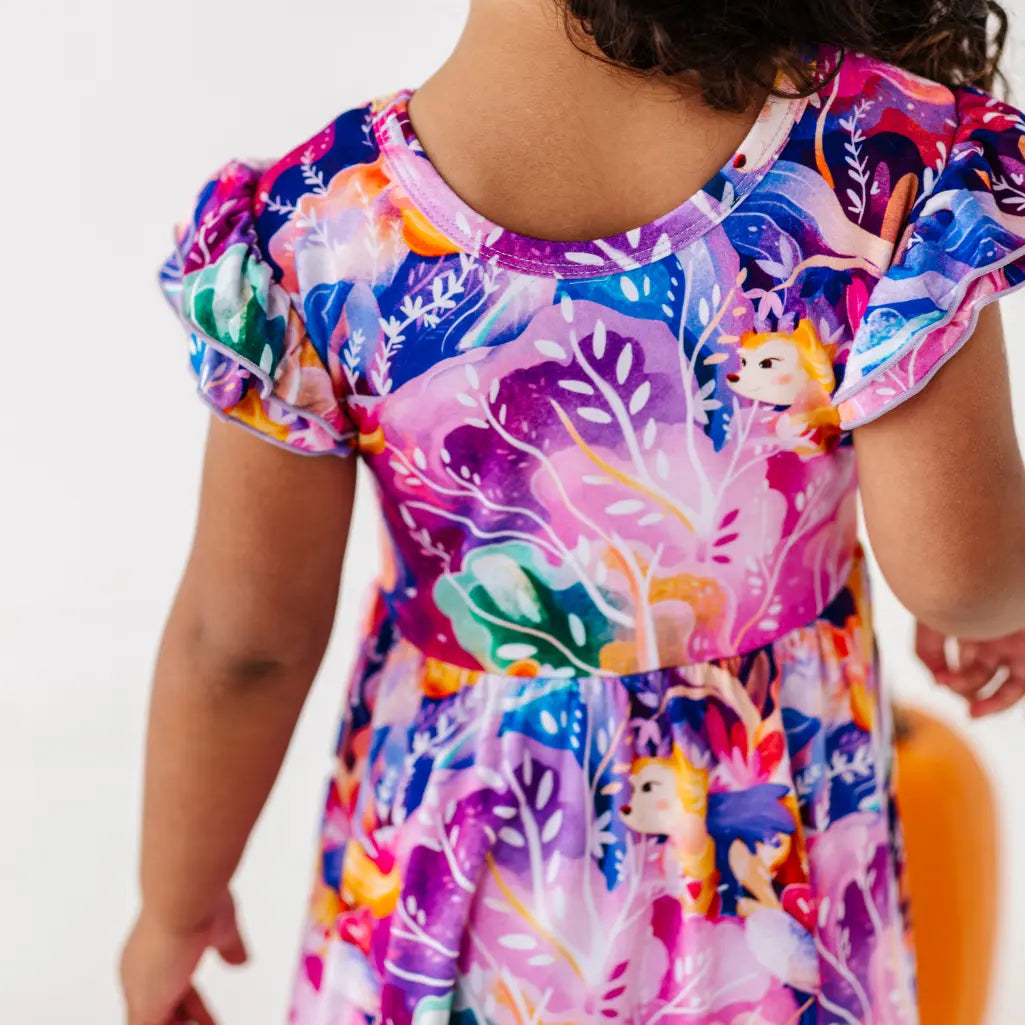 Child wearing a colorful dress with floral and animal prints on a white background