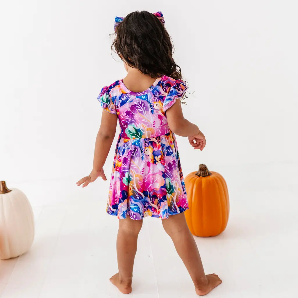 Child wearing a colorful floral dress with pumpkins on a white background