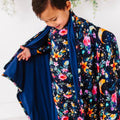 Child wearing a colorful floral and night sky patterned outfit with a blue shawl.