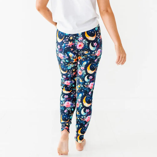 Person wearing dark blue leggings with floral and crescent moon pattern on a white background.
