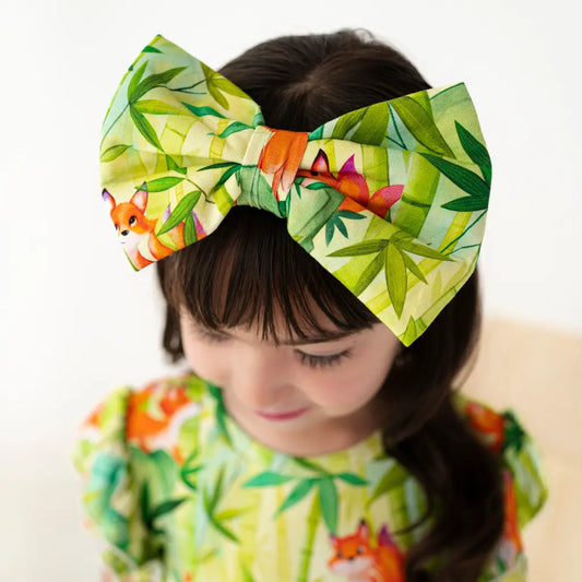 Child wearing a large green headband with fox and leaf pattern