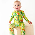 Baby wearing a colorful green and orange floral onesie on a white background