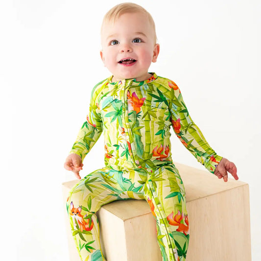 Baby wearing a colorful green and orange floral onesie on a white background