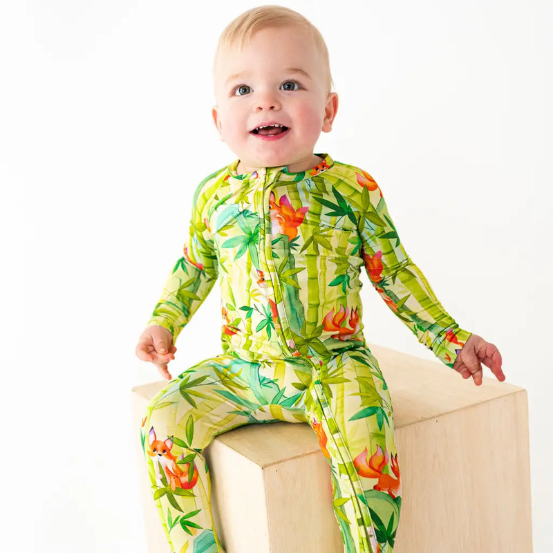 Baby wearing a colorful green and orange floral onesie on a white background