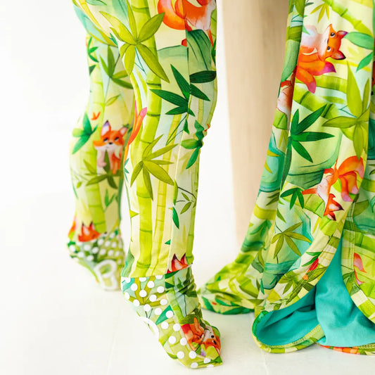 Child wearing tropical print pants with fox and flower pattern on a white background, close-up of legs
