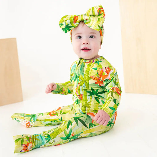 Baby in a green floral outfit with a matching headband on a white background