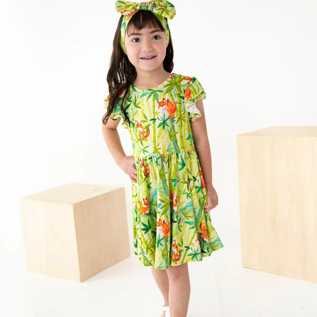 Young girl wearing a colorful floral dress and headband on a white background
