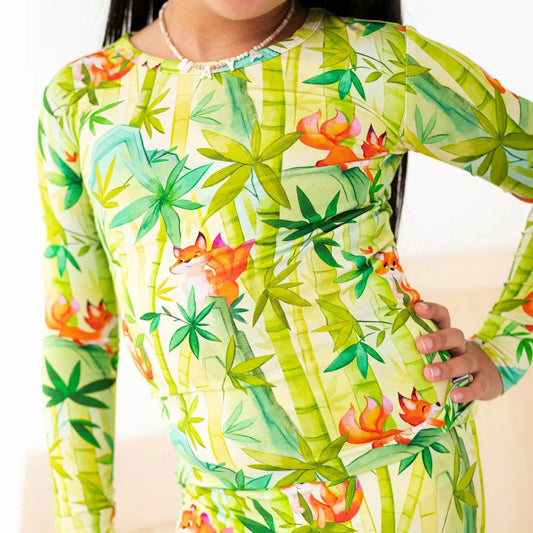Person wearing a long-sleeve shirt with a colorful tropical design featuring bamboo and birds.