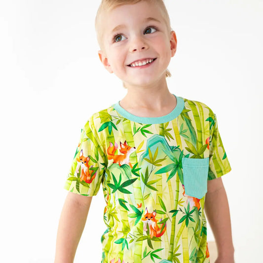 Child wearing a colorful t-shirt with a jungle design on a white background