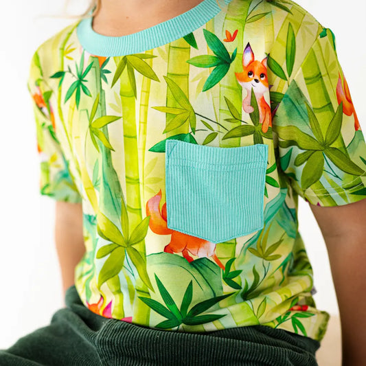 Child's shirt with a fox and jungle leaf pattern on a white background
