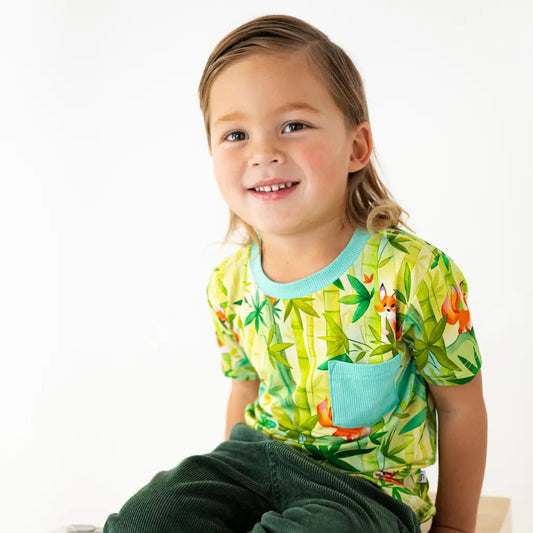 Child wearing a colorful shirt with a nature-themed design on a white background