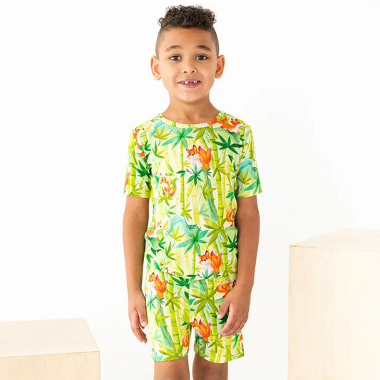 Child wearing a colorful tropical-themed romper on a white background