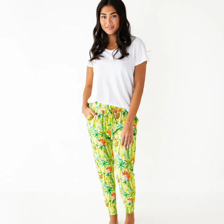 Woman wearing a white t-shirt and colorful tropical print pants on a white background