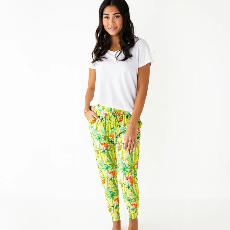 Woman wearing a white t-shirt and colorful tropical print pants on a white background