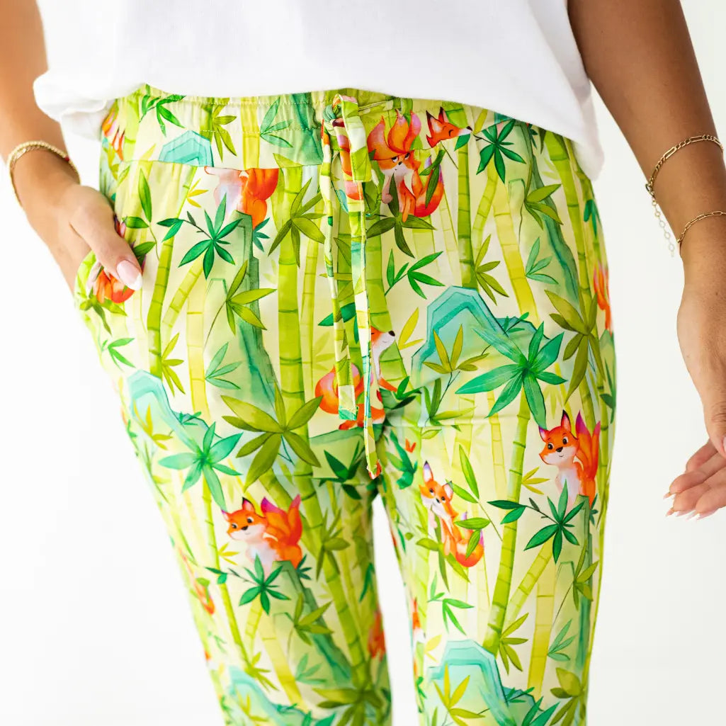 Colorful pants with fox and bamboo pattern worn by a person on a white background