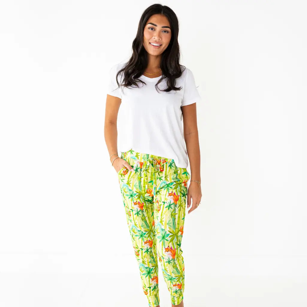 Woman wearing a white t-shirt and colorful tropical print pants on a white background