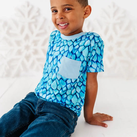 Child wearing a blue patterned shirt with a pocket on a white background