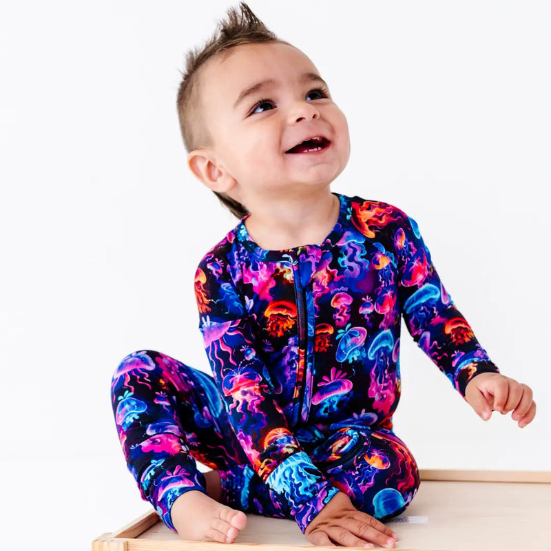 Child wearing a colorful onesie with a jellyfish pattern on a white background