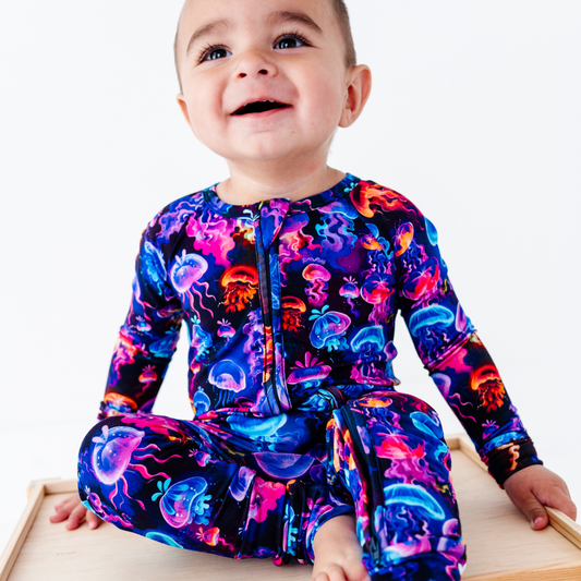 Child wearing a colorful onesie with jellyfish pattern on a white background