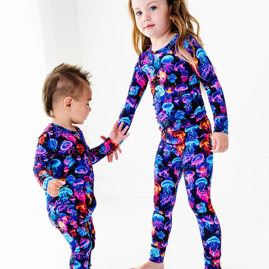Two children wearing colorful jellyfish-patterned outfits on a white background