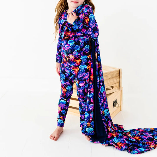 Child wearing a colorful jellyfish patterned onesie with a matching blanket.