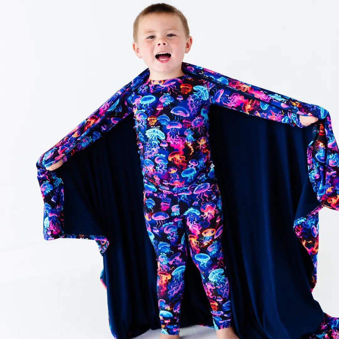 Child wearing a colorful jellyfish-themed costume with a cape on a white background