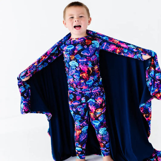 Child wearing a colorful jellyfish-themed costume with a cape on a white background