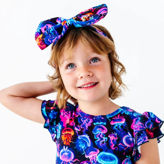 Child wearing a colorful headband and shirt with jellyfish design on a white background