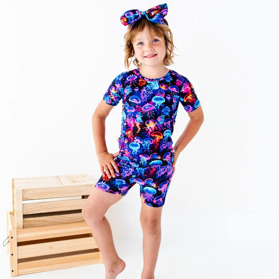 Child wearing a colorful jellyfish-themed outfit with a wooden crate in the background