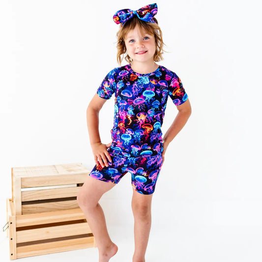 Child wearing a colorful jellyfish-themed outfit with a wooden crate in the background