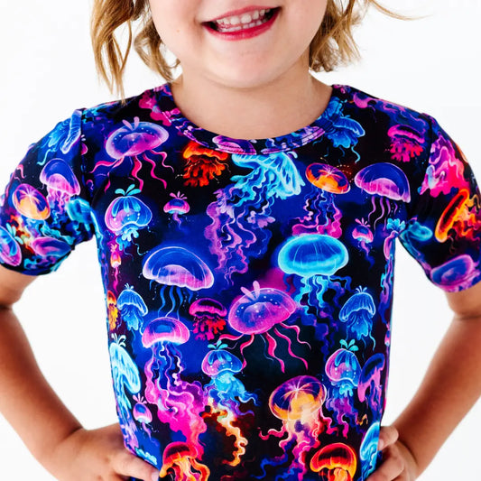 Child wearing a colorful jellyfish patterned shirt on a white background