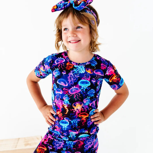 Child wearing a colorful jellyfish-themed dress with a matching headband on a white background