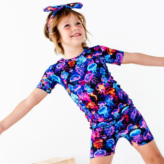Child wearing a colorful jellyfish patterned outfit on a white background