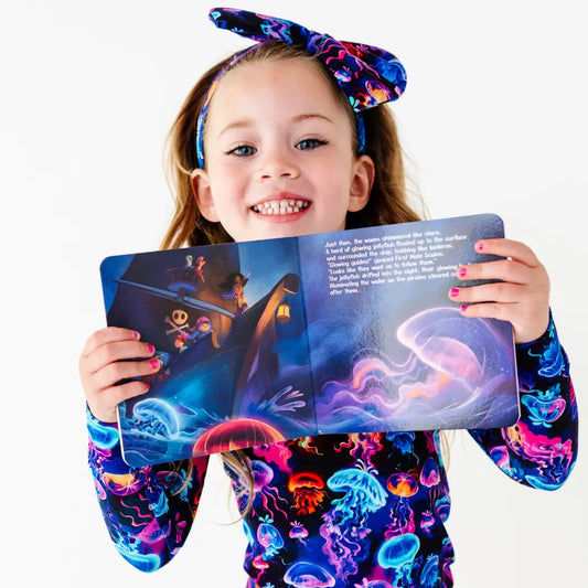Young girl holding a colorful book with a jellyfish illustration on a white background