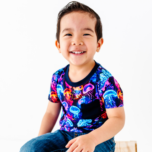 Child wearing a colorful shirt with jellyfish pattern on a white background