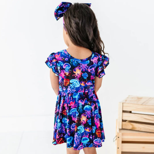 Child wearing a colorful jellyfish-patterned dress on a white background