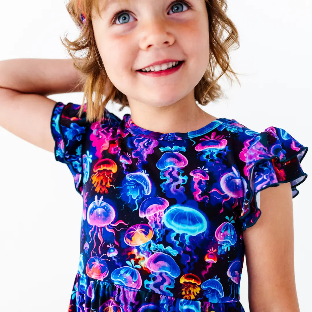 Child wearing a colorful jellyfish-patterned dress on a white background