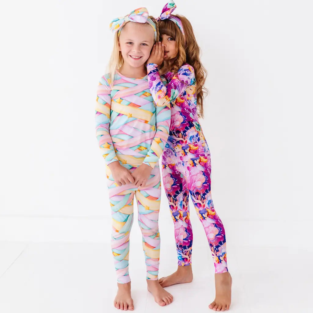 Two children wearing colorful pajamas on a white background