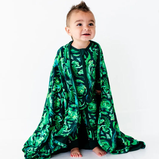 Child wearing a green and black patterned poncho on a white background