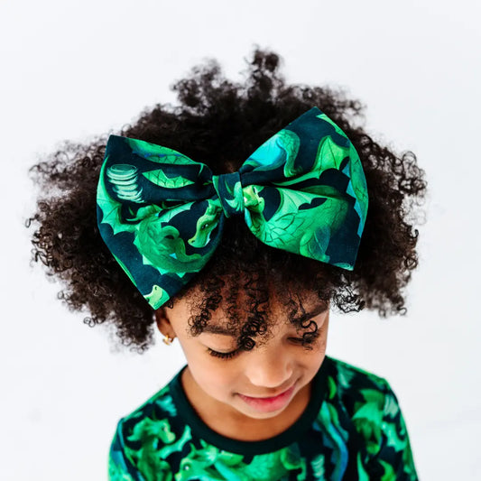Child with large green and black bow in hair against a white background