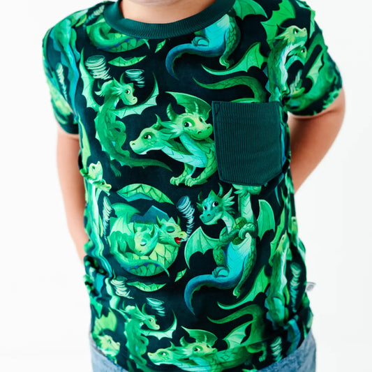 Child wearing a shirt with green dragon pattern on a white background