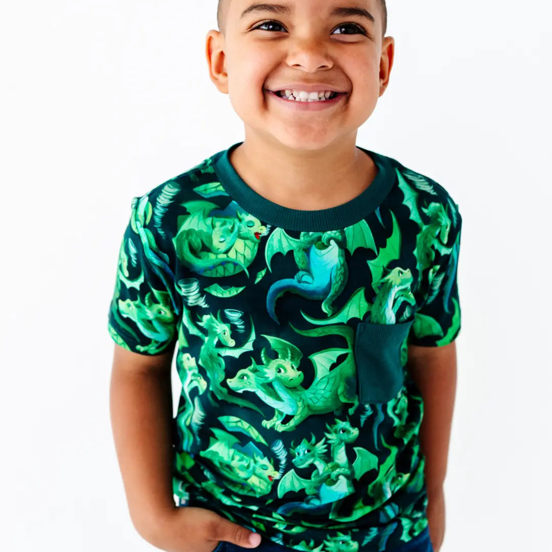 Child wearing a shirt with green dragon pattern on a white background